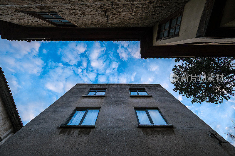 Blue partly cloudy sky seen between adjacent houses